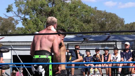 two wrestlers compete in an outdoor ring before audience