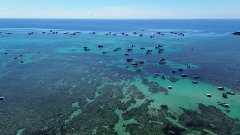 wide panoramic drone shot of fishing vessels positioned over the greenish-blue coastal waters of ninh hải district under bright daylight.