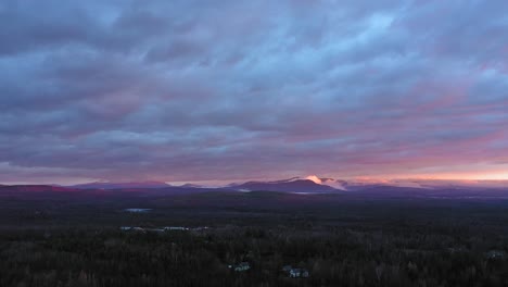 aerial footage flying backwards at sunrise over a late fall forest with misty mountains in the distance