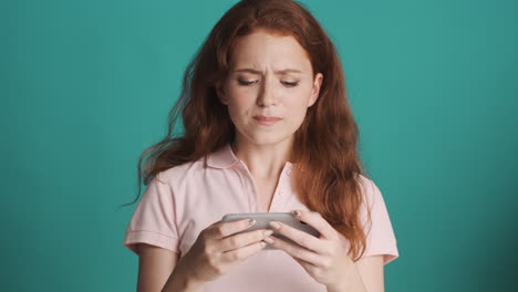 redheaded girl in front of camera on turquoise background.