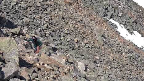 young woman climbing uphill walking on rocks, slope of rocky mountains on sunny day