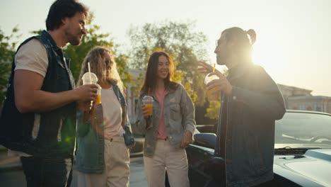 un grupo de jóvenes elegantes y de pie y divertirse cerca de su coche. día soleado y hermosos rayos de sol gran grupo de tiempo caminar