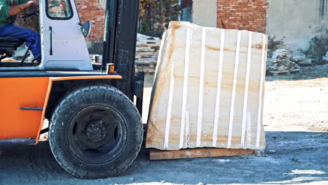 Man driving forklift. Driver loading marble block with equipment