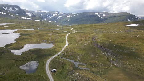 una toma aérea de un dron siguiendo un largo sendero de grava en la cima de vikafjellet en noruega, finalmente revelando un gran lago en la parte superior de la montaña