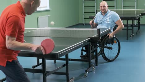 ein mann im rollstuhl spielt ping-pong. menschen mit behinderungen spielen tischtennis. rehabilitation von behinderten. paralympischer sport.