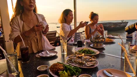 amigos disfrutando de una cena de mariscos al atardecer junto al mar