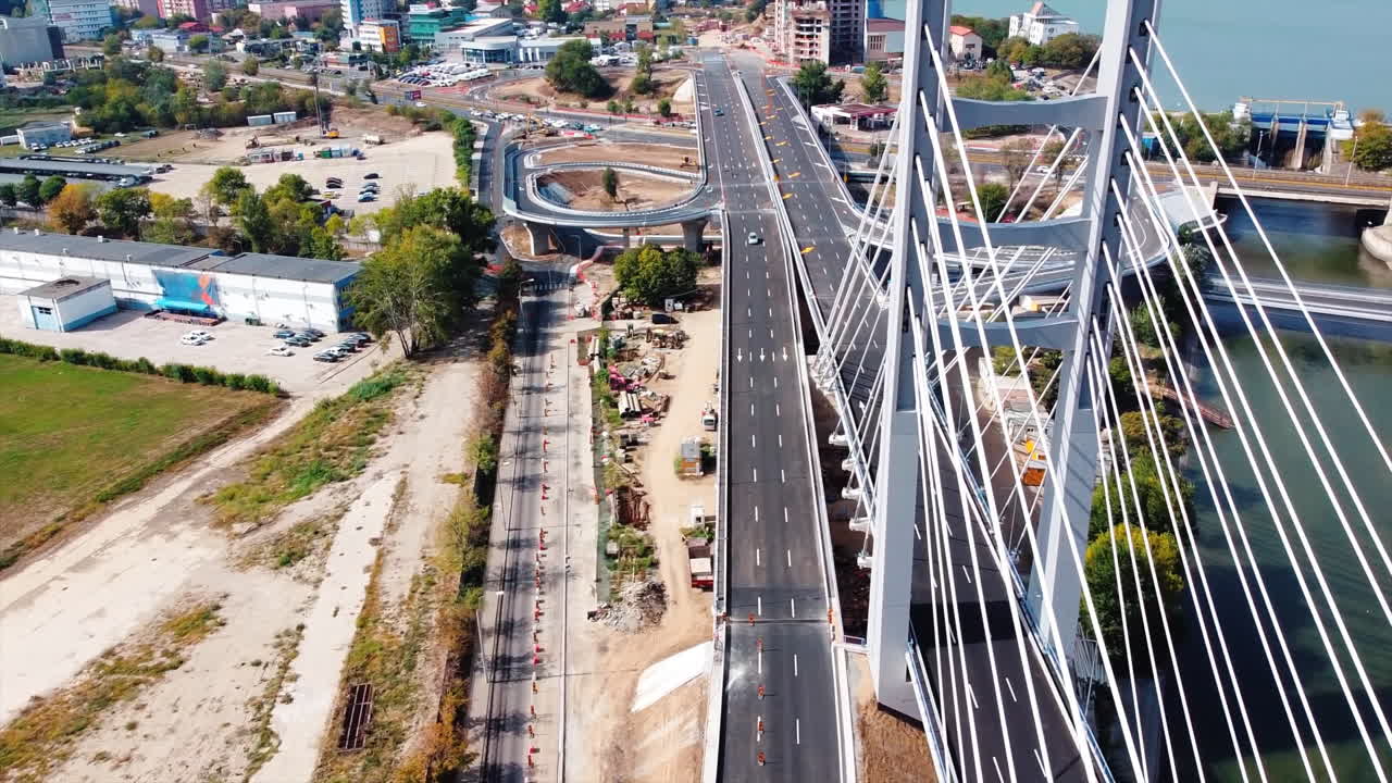 Ciurel passage, bridge over a river with moving cars, construction works, field and TV tower near it. Residential buildings on the background. View from the drone. Bucharest, Romania