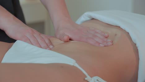 Nahaufnahme-Von-Zwei-Händen-Einer-Masseurin,-Die-Den-Bauch-Einer-Kundin-Knetet;-Sie-Trägt-Einen-Badeanzug