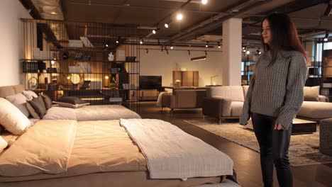 cheerful female customer choosing new bed and mattress to buy at furnishings store. high quality 4k footage