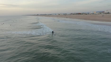 surfers waiting for their waves out in the water as one surfer jumps a wave during golden hour