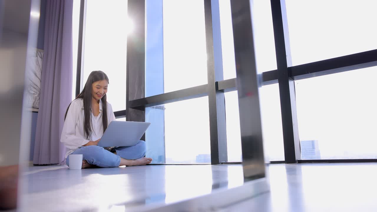 mujer de negocios asiática enfocada trabajando en una computadora portátil, la mujer obtiene una nueva oportunidad de trabajo a distancia, lee buenas noticias en el correo electrónico, se siente motivada. sol matutino iluminando la habitación.