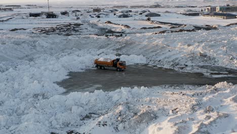 aerial orbit shot of truck transporting snow after strong snowfall at night in selfoss, iceland