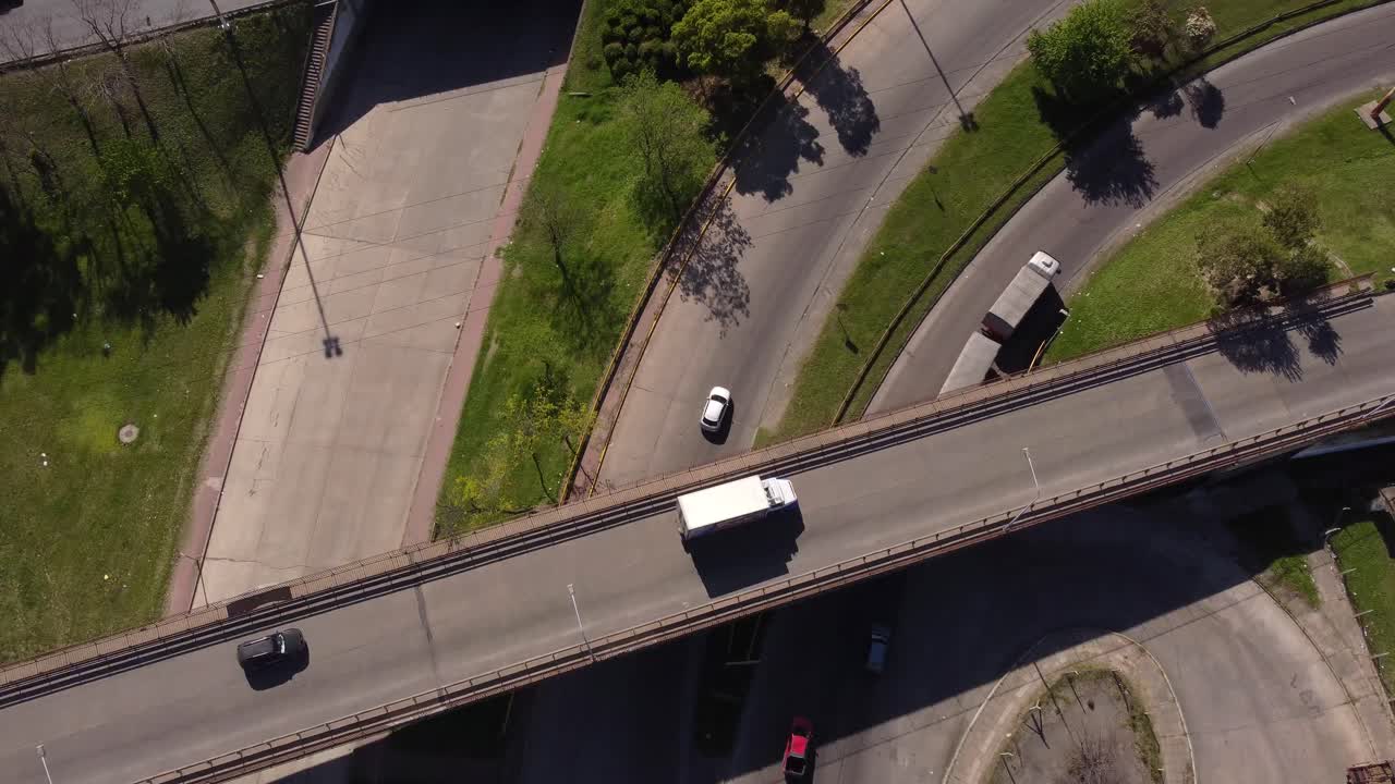 Vista aérea cenital de camión saliendo de la autopista, pasando por debajo de un puente en una intersección gigante en Buenos Aires