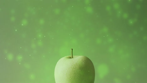 composition of green apple over spots of light on green background