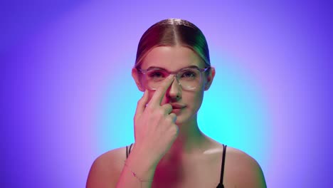 attractive blonde young woman adjusts reading glasses, sexy studious attitude, close-up shot of semi-naked torso in studio