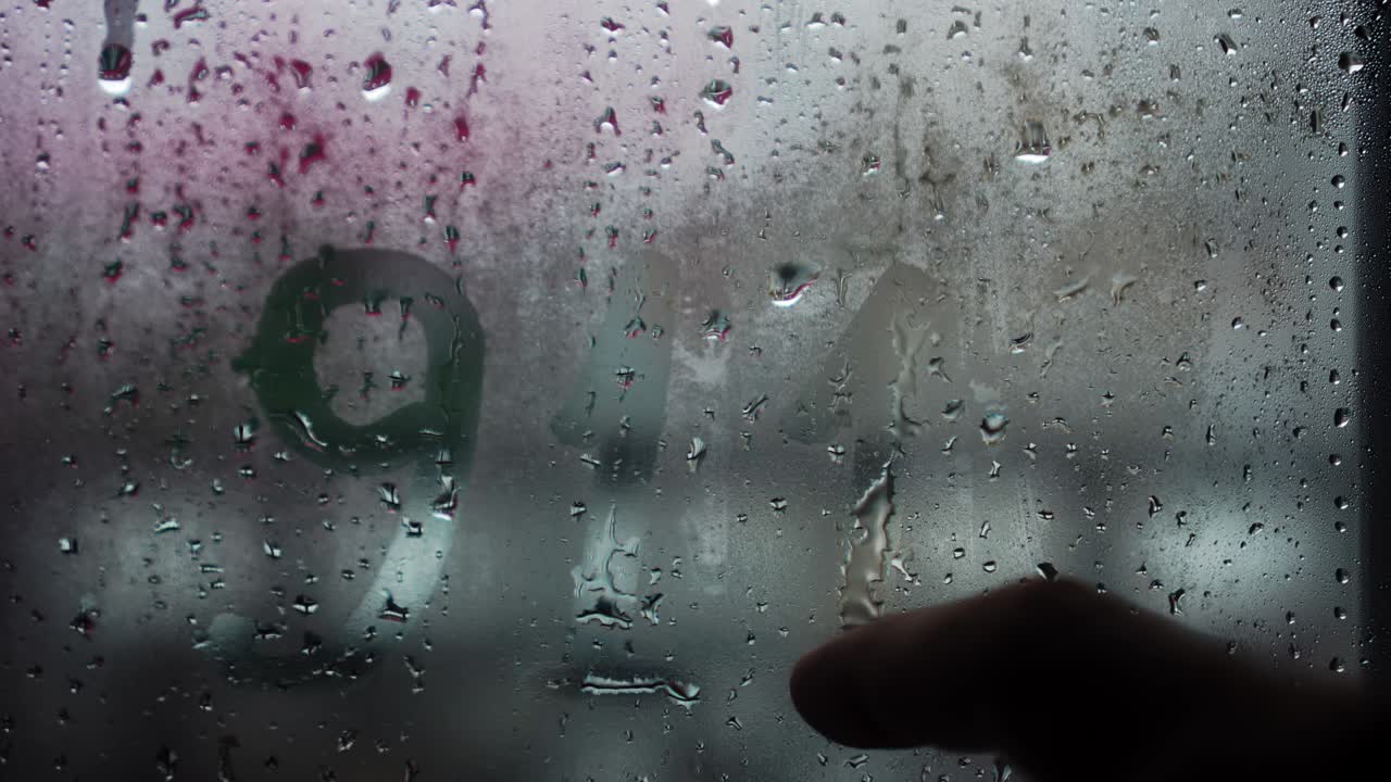 "영국어로 ""911""라는 문구가 얼어붙은 유리 위에 새겨져 있다."