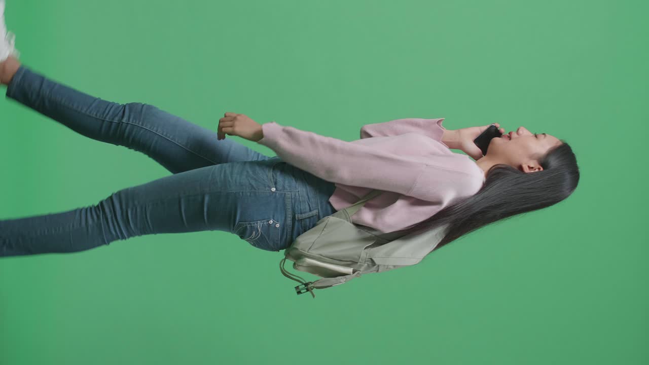 녹색 스크린 스튜디오에서 는 동안 휴대전화로 대화하는 아시아 여성 학생의 측면 시각