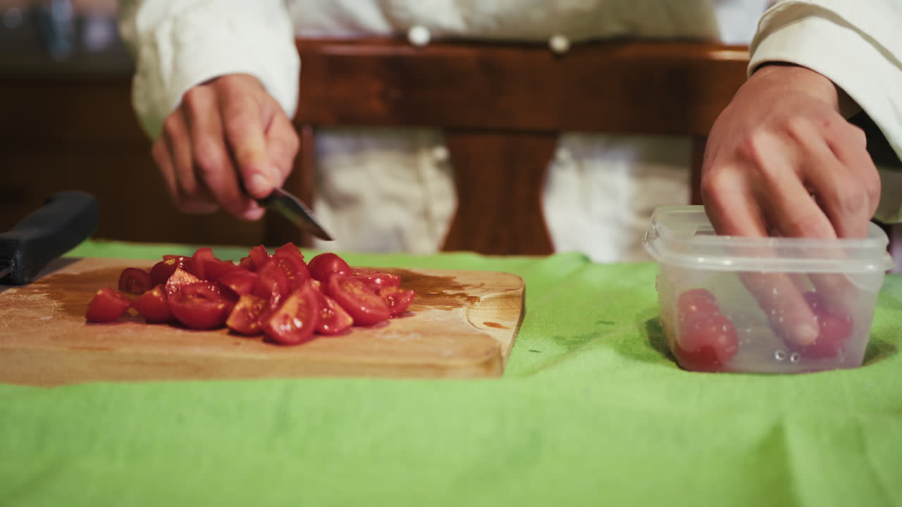 Man's Hands Cut Cherry Tomatoes On A Wooden Cutting Board In The Kitchen
