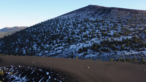 aerial: snow covered volcanic mountain region at sunset crater, flagstaff - drone shot