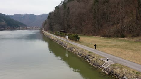 Gefilmt-Direkt-Auf-Der-Anderen-Seite-Des-Flusses-In-Richtung-Einer-Wunderschönen-Dunklen-Herbstlandschaft-Mit-Kleinen-Hügeln-Im-Hintergrund