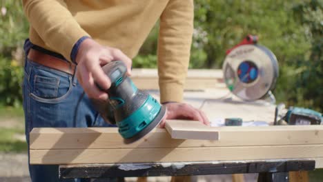 the craftsman grinds the wood with the grinding machine