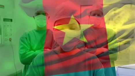 Kamerun-flagge-Weht-Gegen-Das-Porträt-Eines-Chirurgenteams,-Das-Im-Krankenhaus-Gesichtsmasken-Trägt