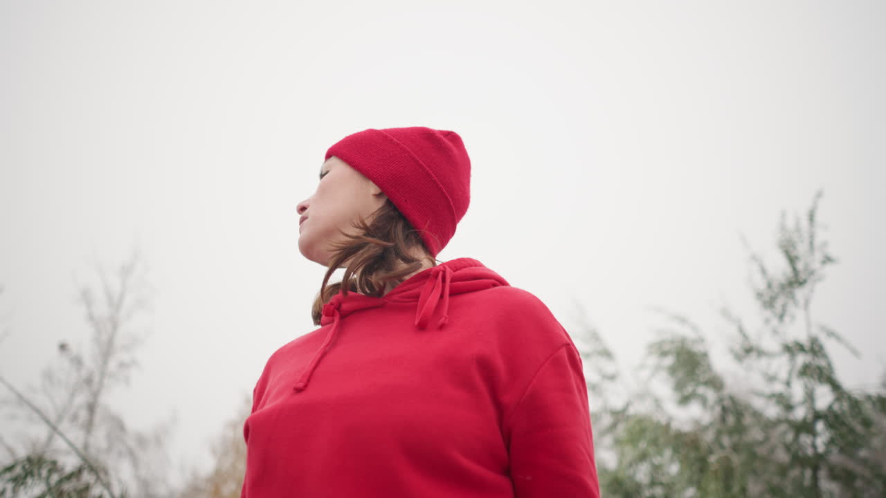 중년 여성은 안개가 가득한 분위기 아래에서 머리를 오른쪽에서 왼쪽으로 돌리고, 배경에는 흐릿한 나무가 있으며, 부드럽고 조용한 자연 장면은 안개 환경에서 평온과 성찰을 불러일으킨다.