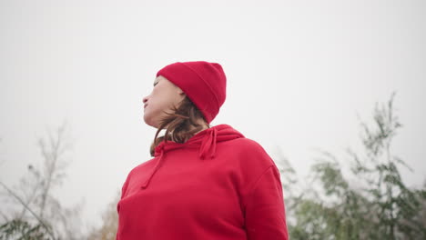 middle-aged woman turning head from right to left under foggy atmosphere with blurred trees in background, soft and serene nature scene evoking calm and contemplation in misty environment