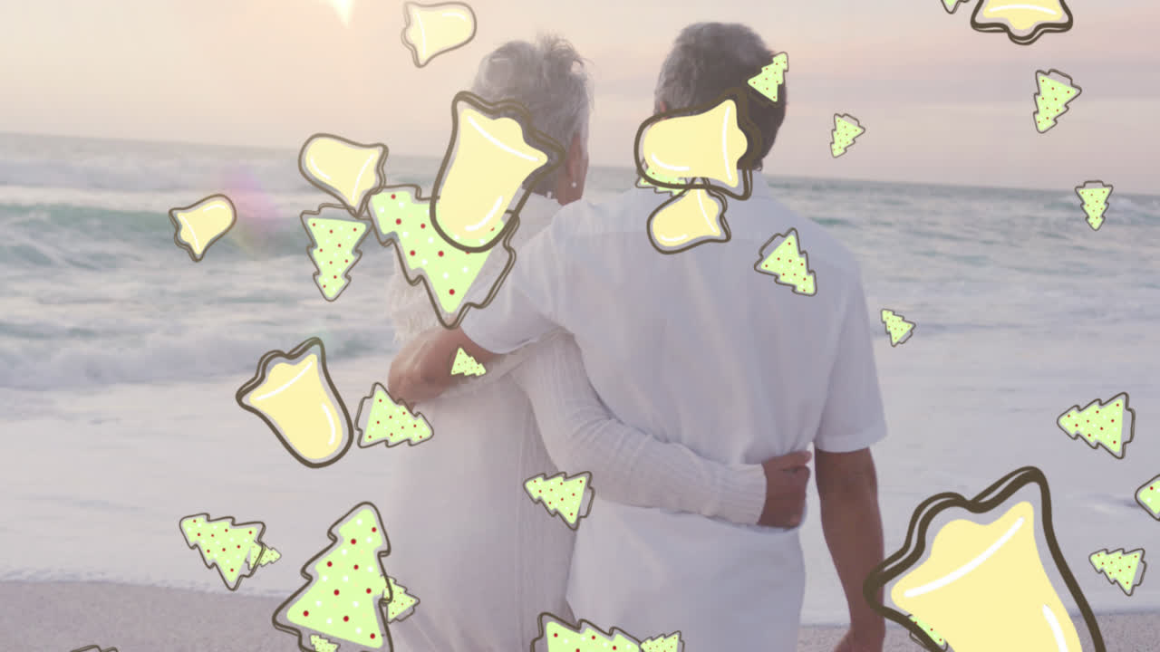 크리스마스 트리 및 종 아이콘의 애니메이션이 해변에서 고령 미인 부부 위에 있습니다.