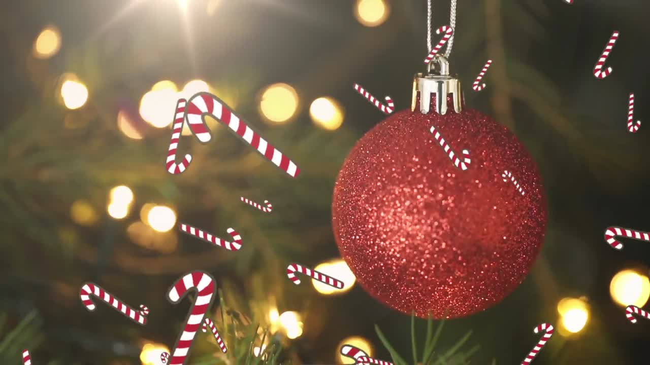 múltiples iconos de caña de caramelo cayendo contra la joya roja colgando sobre las ramas del árbol de navidad