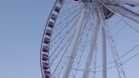 shot of the side of a ferry-wheel with red capsules during the day with a clear blue sky