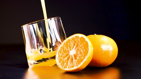 juice pouring into glass with fresh oranges