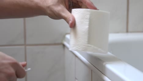 Man-grabbing-a-roll-of-toilet-paper,-and-taking-some-to-wipe