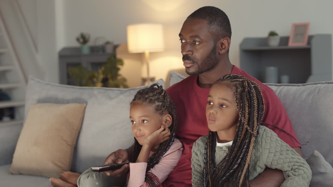 Padre e figlie che guardano la TV a casa