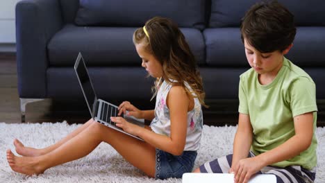 siblings using laptop in living room