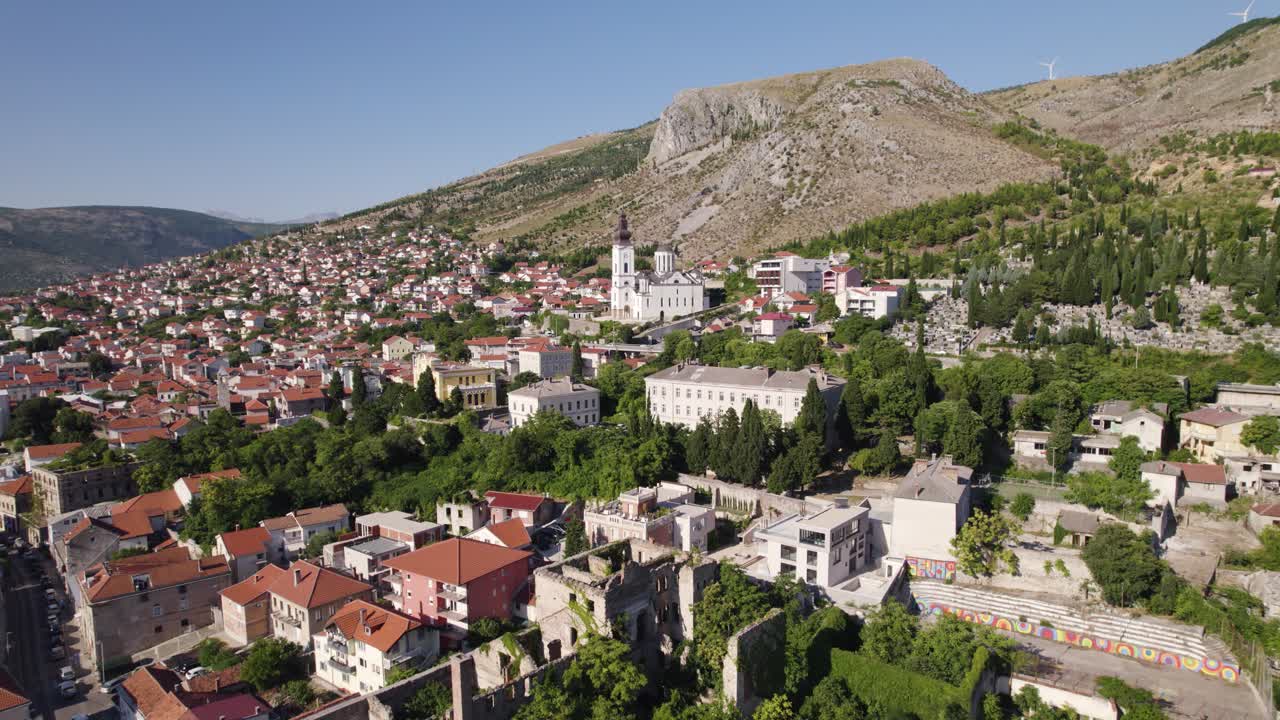 Aerial view of Mostar cityscape featuring the Cathedral of Mary, Mother of the Church and Hum Hill in Bosnia and Herzegovina. Pull Back Shot
