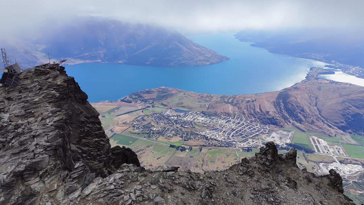 Aerial orbits telecom tower on rugged mtn top at Queenstown New Zealand