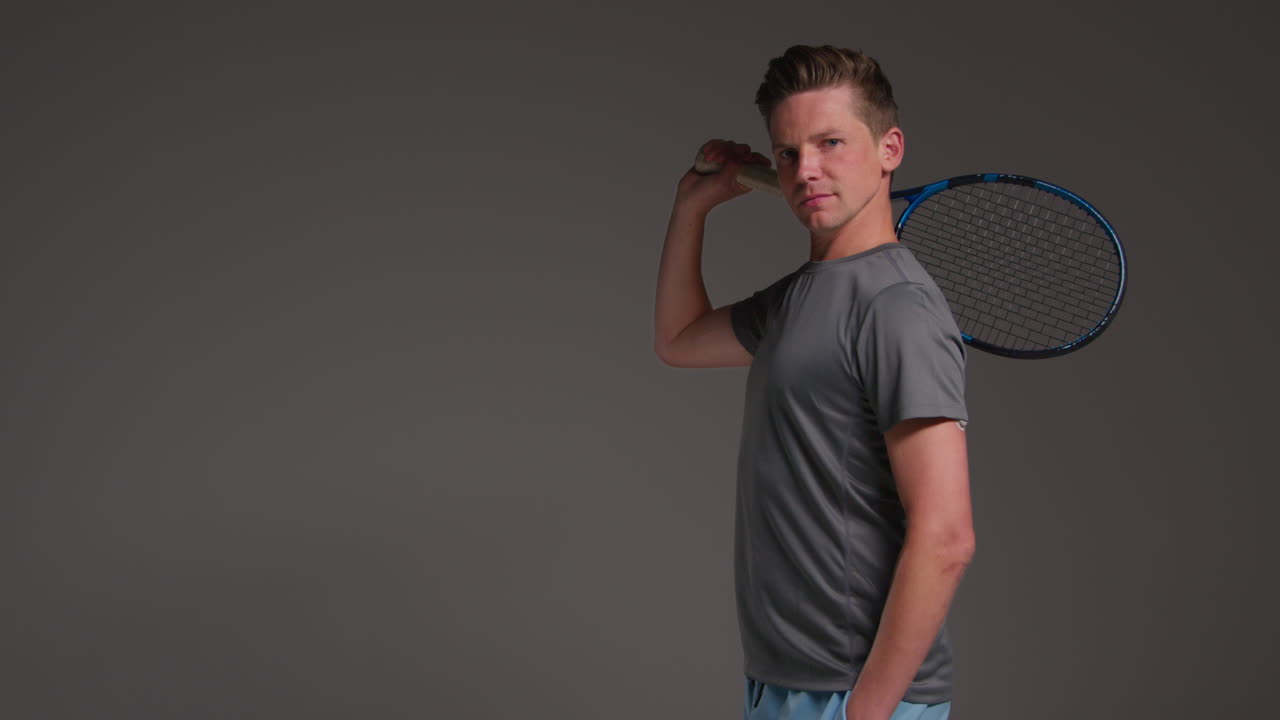 retrato de estudio de un jugador de tenis masculino sosteniendo una raqueta contra un fondo gris 2