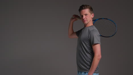 Studio-Portrait-Of-Male-Tennis-Player-Holding-Racket-Shot-Against-Grey-Background-2