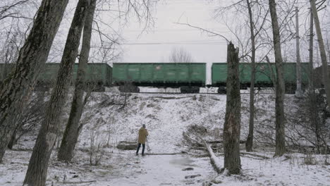 timelapse of man shooting video of cargo train passing by