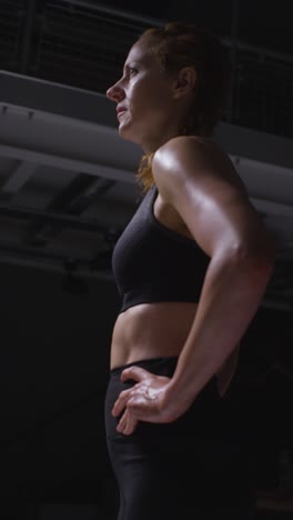 vertical video shot of mature woman wearing gym fitness clothing sweating recovering after exercise