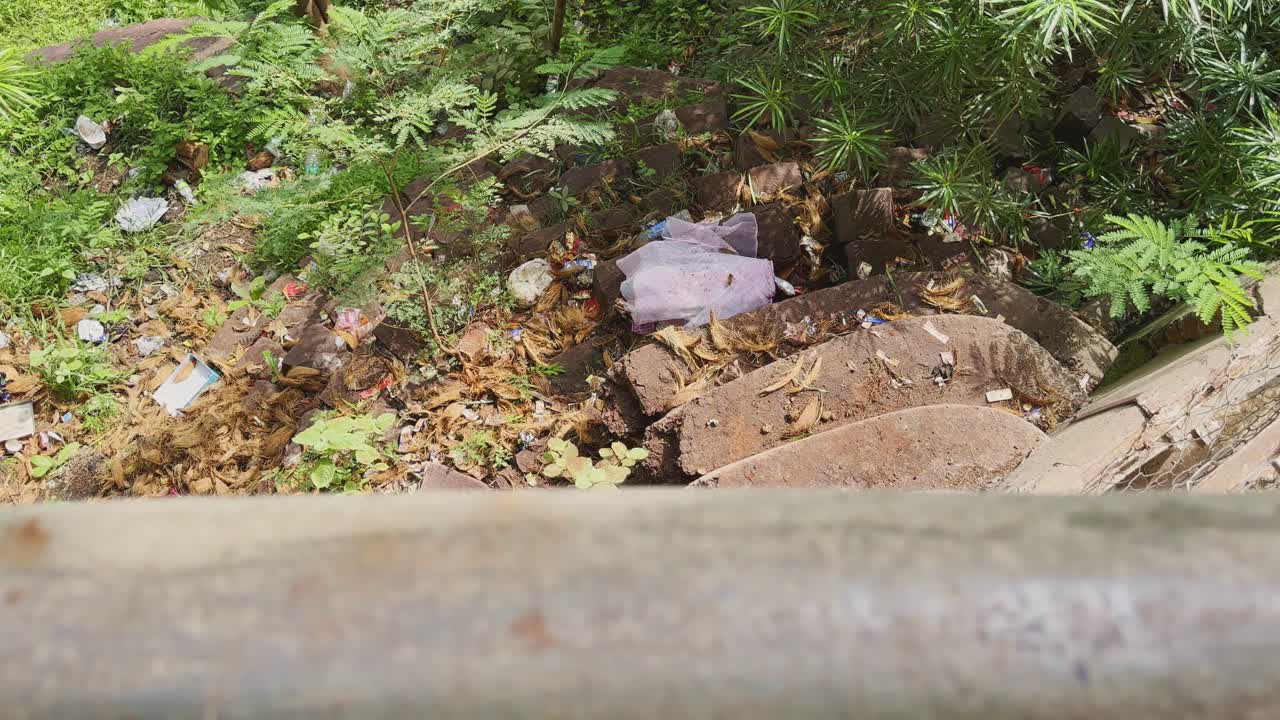 Push-in shot showing discarded coconut peels and garbage thrown near the steps of a religious site in India