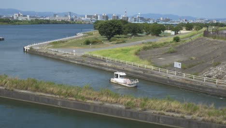 tugboat navigating in yodo river towards the kema lock gate in osaka, japan. - wide shot