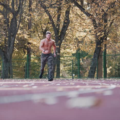 muscular man is training on outdoor stadium. young sportsman without shirt running during his workout on athletics track. healthy lifestyle.