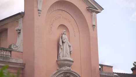 gros plan sur la statue de sainte geneviève, surplombant la porte de l’église sainte geneviève à asnières-sur-seine, avec une lumière douce mettant en valeur la sculpture religieuse.