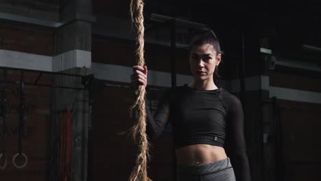 young woman posing in the gym with climbing rope