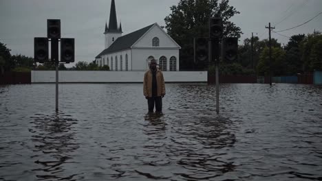 floodwaters from a devastating natural disaster engulfing a man and loudspeakers near a church, illustrating the dramatic effects of climate change on vulnerable communities
