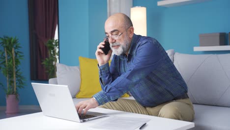 el viejo que habla por teléfono trabaja en una computadora portátil.
