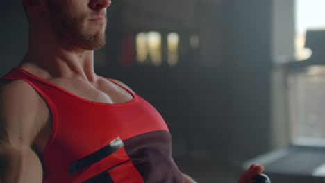 hombre atlético sin camisa haciendo ejercicios en la espalda con una máquina de ejercicio de potencia en un club de gimnasio. vista lateral de un hombre musculoso que usa una máquina de remo en el gimnasio