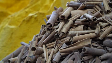 Rack-focus-of-spices-in-Moroccan-market,-cinnamon-stick-and-turmeric-powder